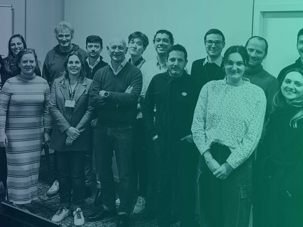 Group photo of workshop attendees and GRASFI Board and staff at EDHEC Business School with blue-green gradient overlay